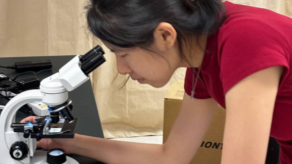 Female researcher looking through microscope
